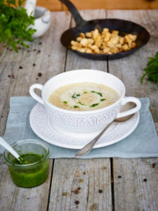 Wine cream soup in soup cup, parsley pesto in a glass jar, hand-forged iron pan with croutons, table with untreated table top Wine cream soup in soup cup, parsley pesto in a glass jar, hand-forged iron pan with croutons, table with untreated table top
